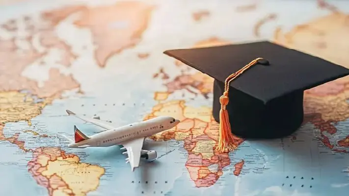 Graduation cap and airplane placed on a world map representing study abroad opportunities, international education and global student travel.